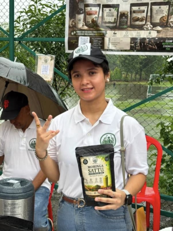 Founder holding a pack of Moringa Sattu at the event stall